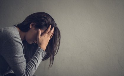 Depressed woman sitting on a chair in dark room at home. Lonly , sad, emotion concept.